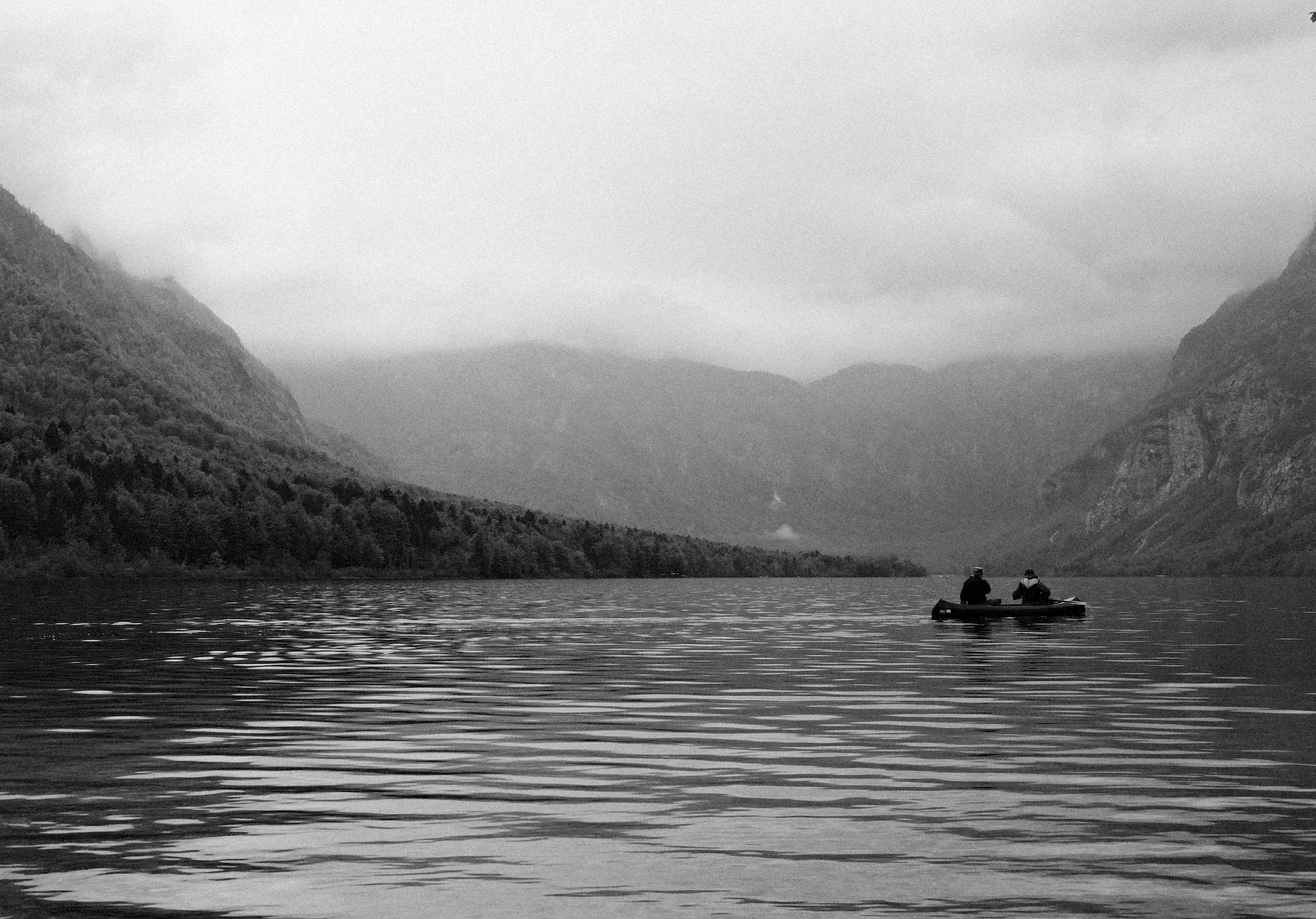 Two people sit on a boat in the middle of Lake Bohinj, Slovenia